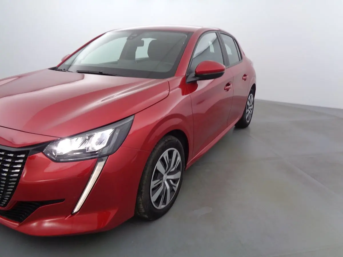 Peugeot 208 rouge Elixir métal vue 3/4 avant droit avec phares allumés sur fond neutre.