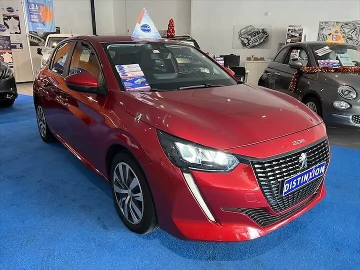 Peugeot 208 rouge Elixir Metal vue 3/4 avant droit dans un showroom avec éclairage intérieur.