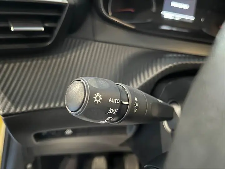 Gros plan sur la commande des feux du tableau de bord d'une Peugeot 208 rouge Elixir Metal, version 2020.