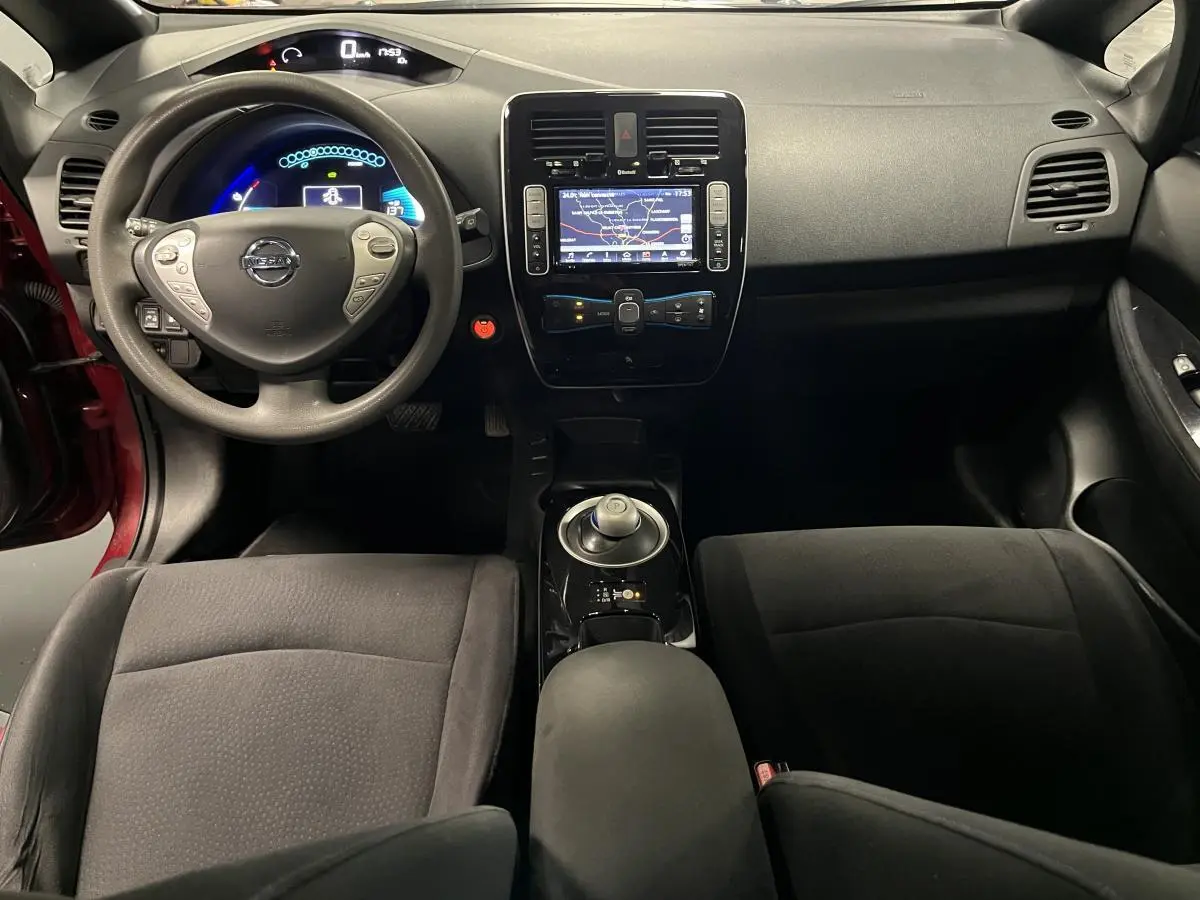 Vue intérieure avant de la Nissan Leaf 30 2017 rouge, mettant en valeur le tableau de bord et la console centrale noire.