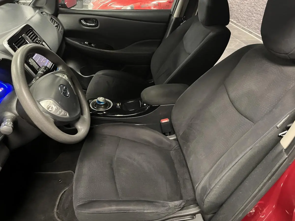 Intérieur avant droit d'une Nissan Leaf 2017 rouge, sièges tissu noirs et volant multifonction avec commandes intégrées.