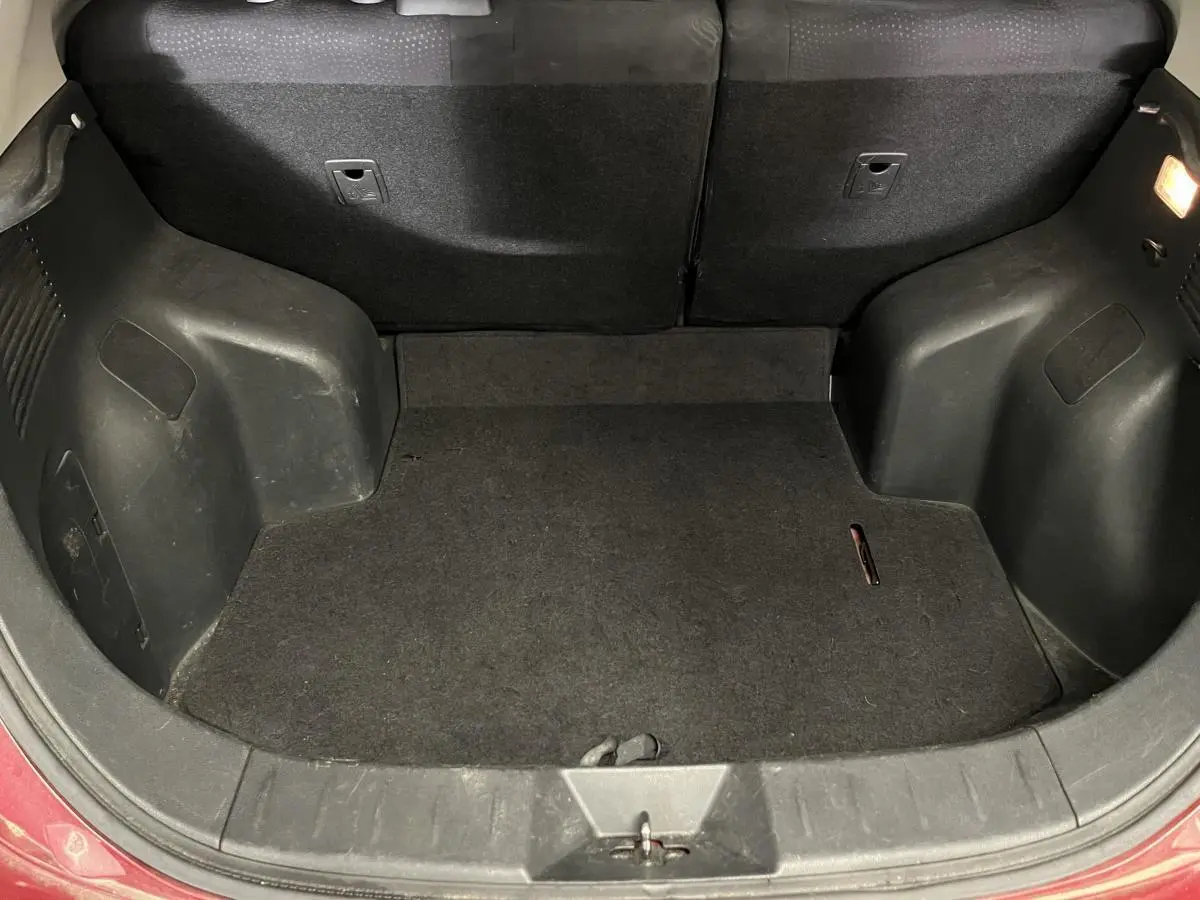 Coffre ouvert vu de face d'une Nissan Leaf rouge 2017, montrant l'espace de chargement vide et la garniture noire.