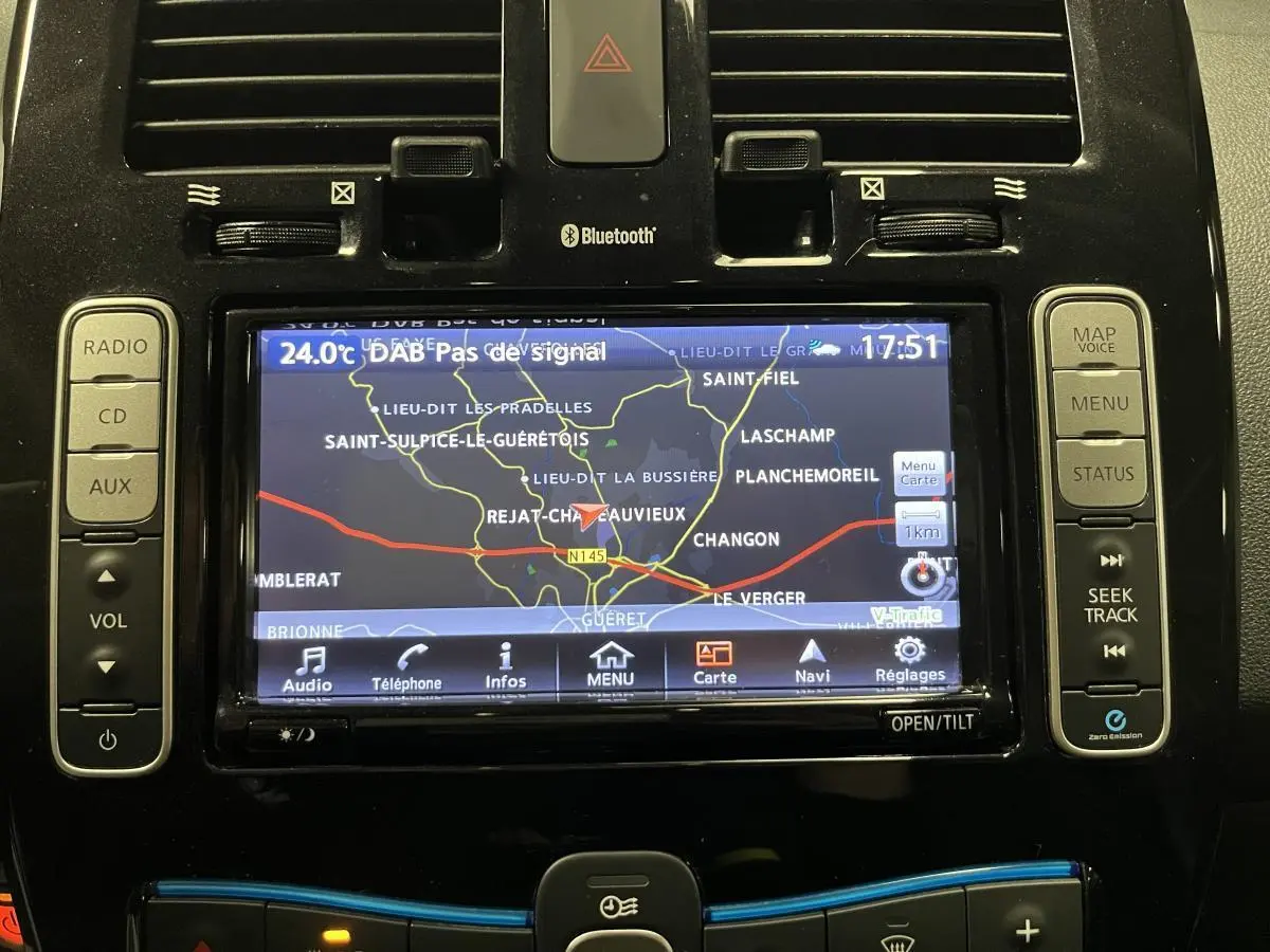 Écran tactile central du tableau de bord de la Nissan Leaf rouge 2017 affichant la navigation GPS et commandes audio.
