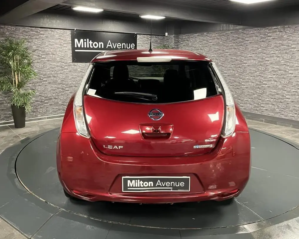 Vue arrière d'une Nissan Leaf rouge métallisée 2017 avec logo et badges électriques visibles en intérieur showroom.