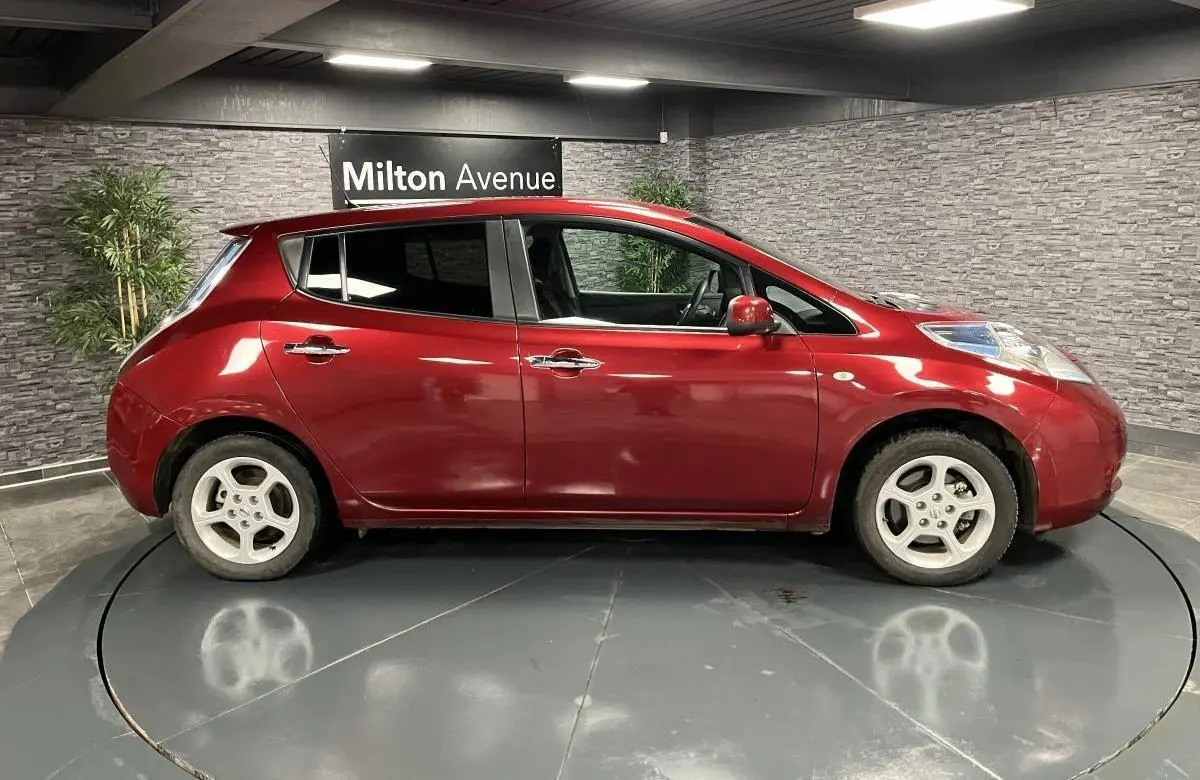 Profil côté gauche d'une Nissan Leaf 30 Visia rouge métallisée de 2017, stationnée en intérieur sur plateau tournant.