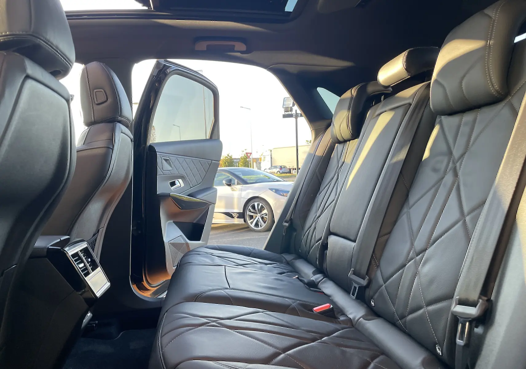 Vue intérieure arrière droite du DS7 2024 noir Perla Nera, montrant les sièges en cuir noir matelassé et la portière ouverte.