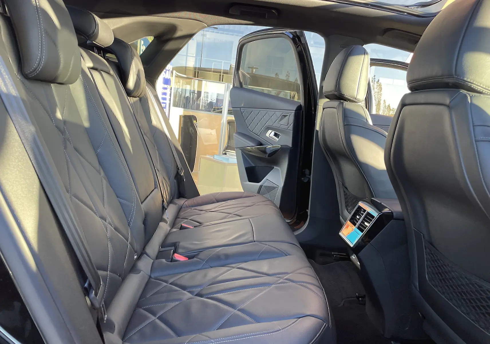 Vue intérieure arrière droite du DS7 2024 noir Perla Nera, sièges cuir noir matelassé et porte arrière ouverte.