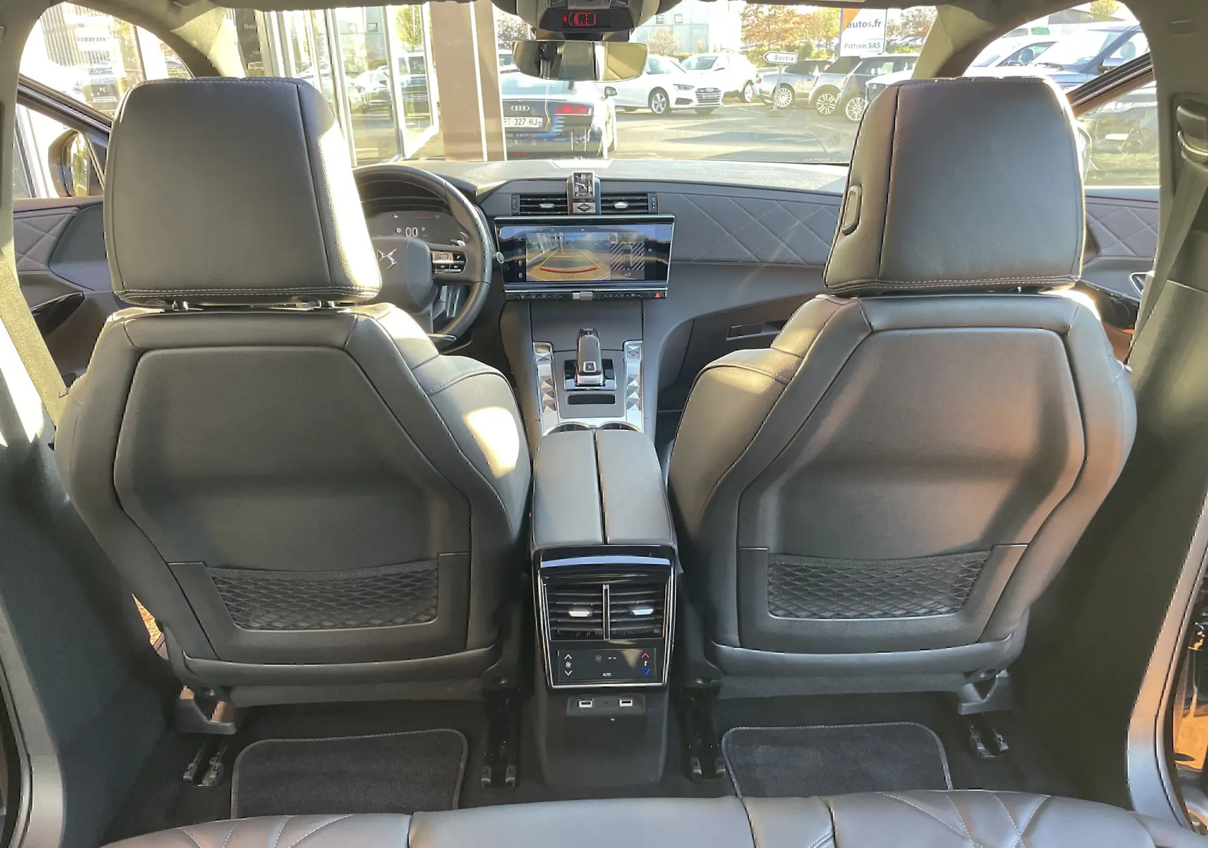 Vue arrière de l'intérieur noir cuir du DS7 2024, montrant les sièges avant et la console centrale avec écran tactile.