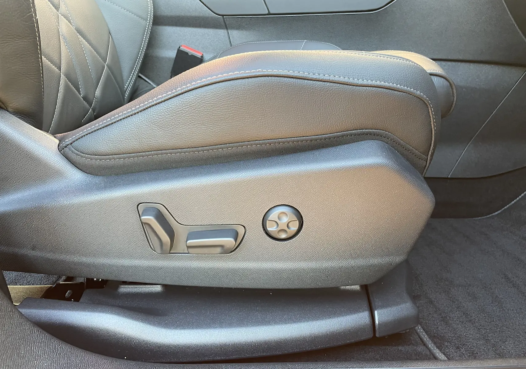 Gros plan sur les commandes de réglage électrique du siège avant en cuir noir du DS7 2024 côté gauche.