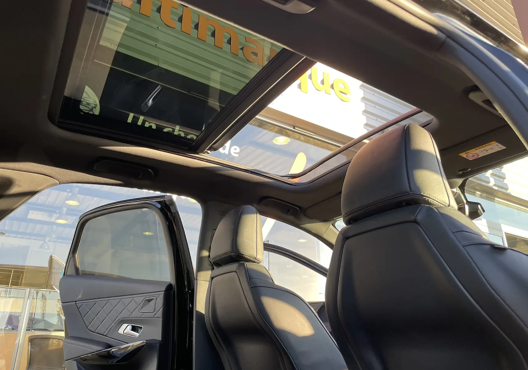 Vue intérieure arrière du DS7 2024 noir Perla Nera, avec toit ouvrant panoramique et sièges en cuir noir.