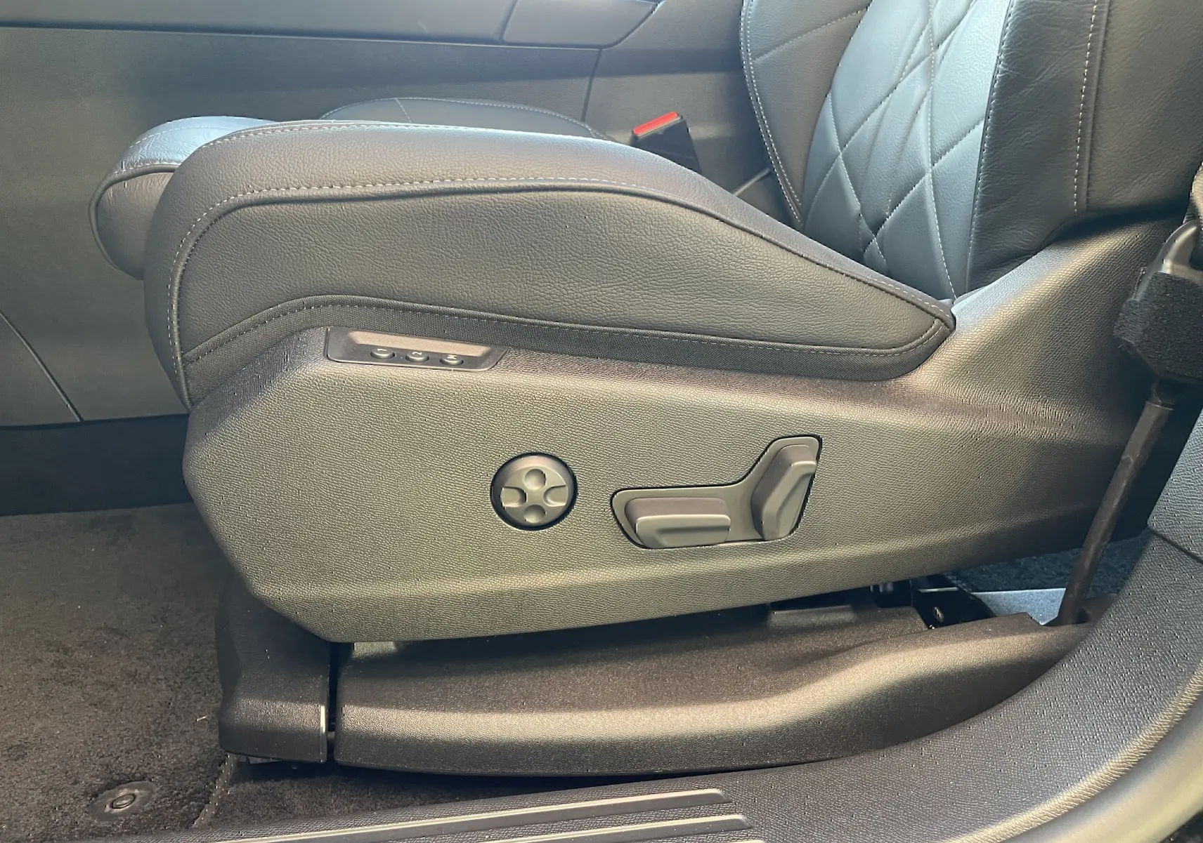 Gros plan sur les commandes de réglage électrique du siège avant gauche en cuir noir du DS7 2024 Noir Perla Nera.
