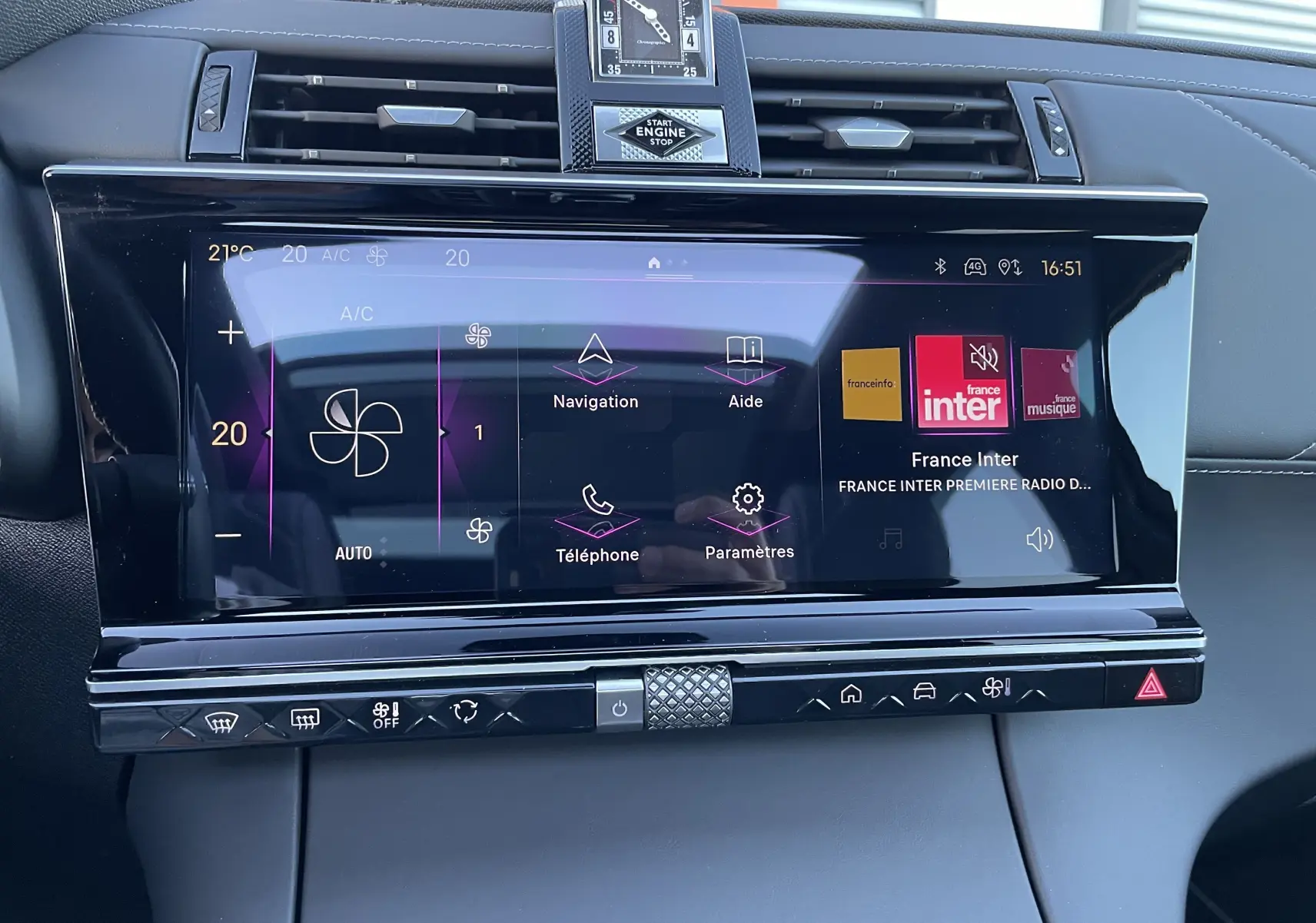 Écran tactile central du DS7 2024 noir Perla Nera, affichant la climatisation et la radio France Inter, avec horloge analogique intégrée.