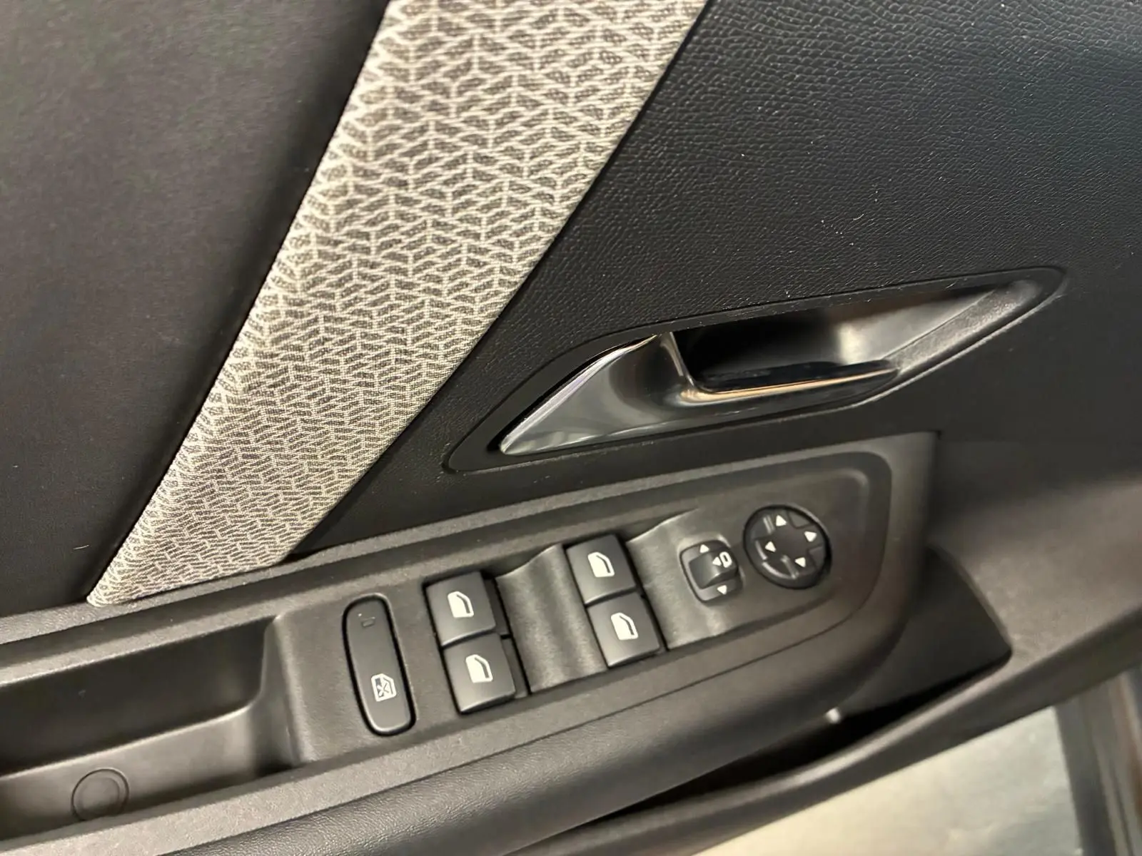 Gros plan sur la commande des vitres et la poignée intérieure côté gauche d’une Citroën C4 X gris, tissu gris-noir.