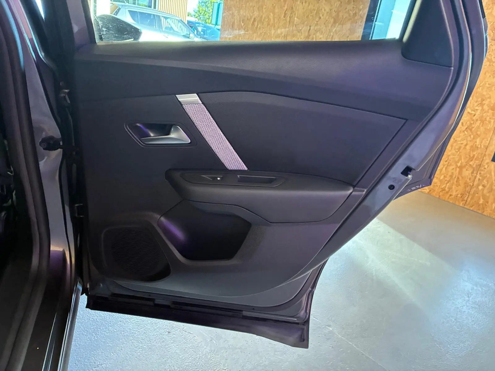 Vue intérieure de la porte arrière gauche d'une Citroën C4 X gris, avec garniture noire et insert décoratif argenté.