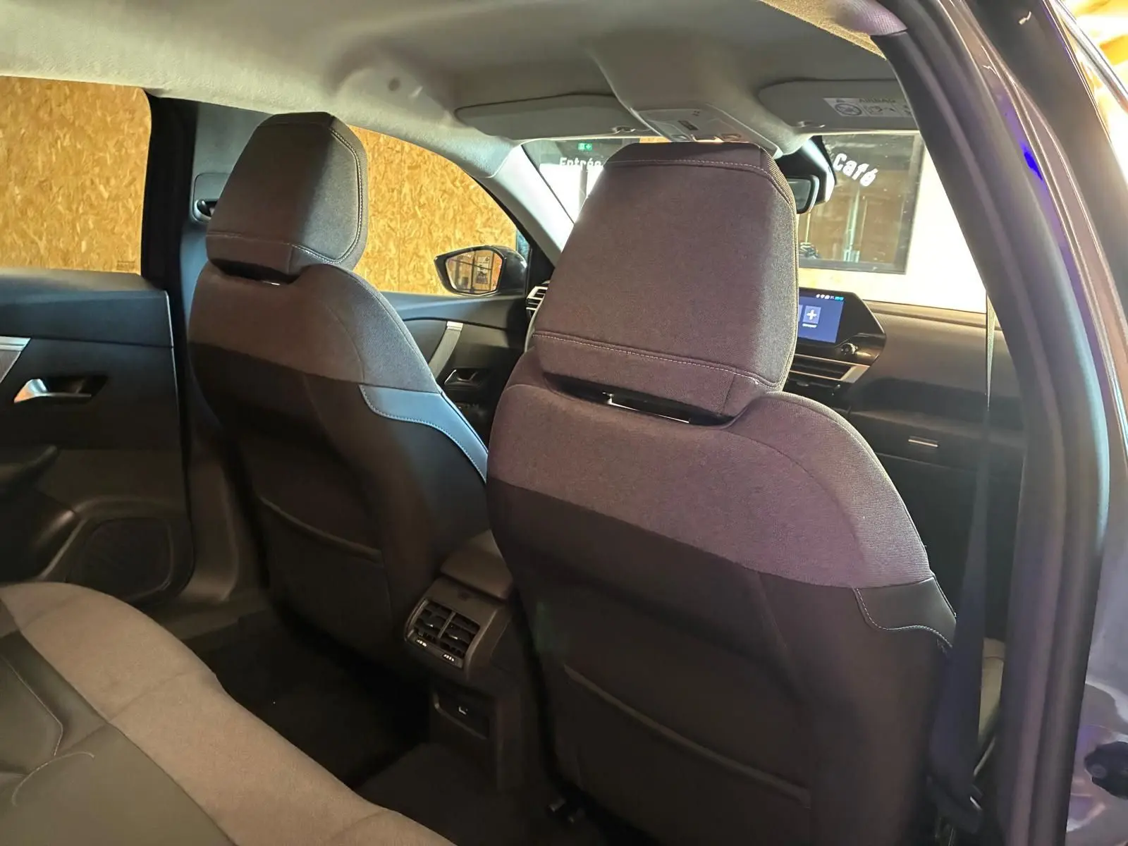 Vue intérieure arrière du Citroën C4 X gris 2024, montrant les sièges avant en tissu gris et la console centrale avec aérateurs.