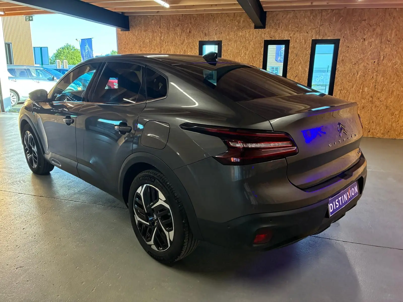 Vue 3/4 arrière droite d'une Citroën C4 X gris métallisé 2024 avec feux arrière LED et jantes bicolores.