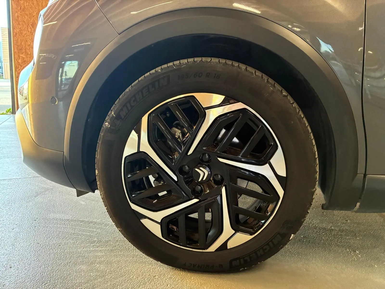 Gros plan sur la roue avant gauche d'une Citroën C4 X gris 2024, jante alliage bicolore au design moderne.