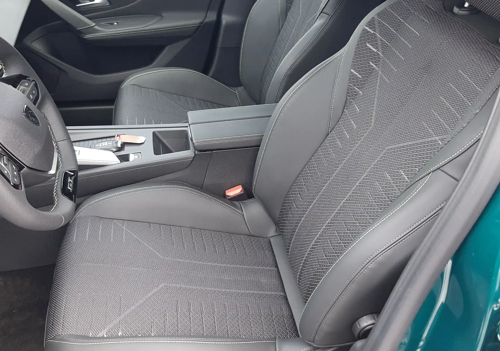 Intérieur avant droit de la Peugeot 308 Bleu Lagoa 2025, sièges en tissu et cuir noir avec surpiqûres grises.