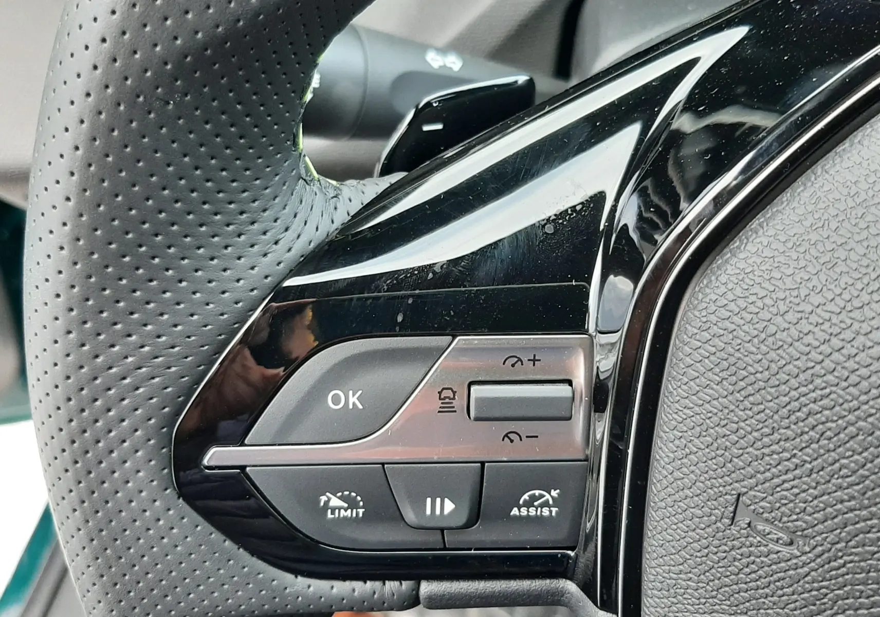 Gros plan sur les commandes gauche du volant perforé noir du Peugeot 308 1.2 Hybrid 145ch GT 2025.