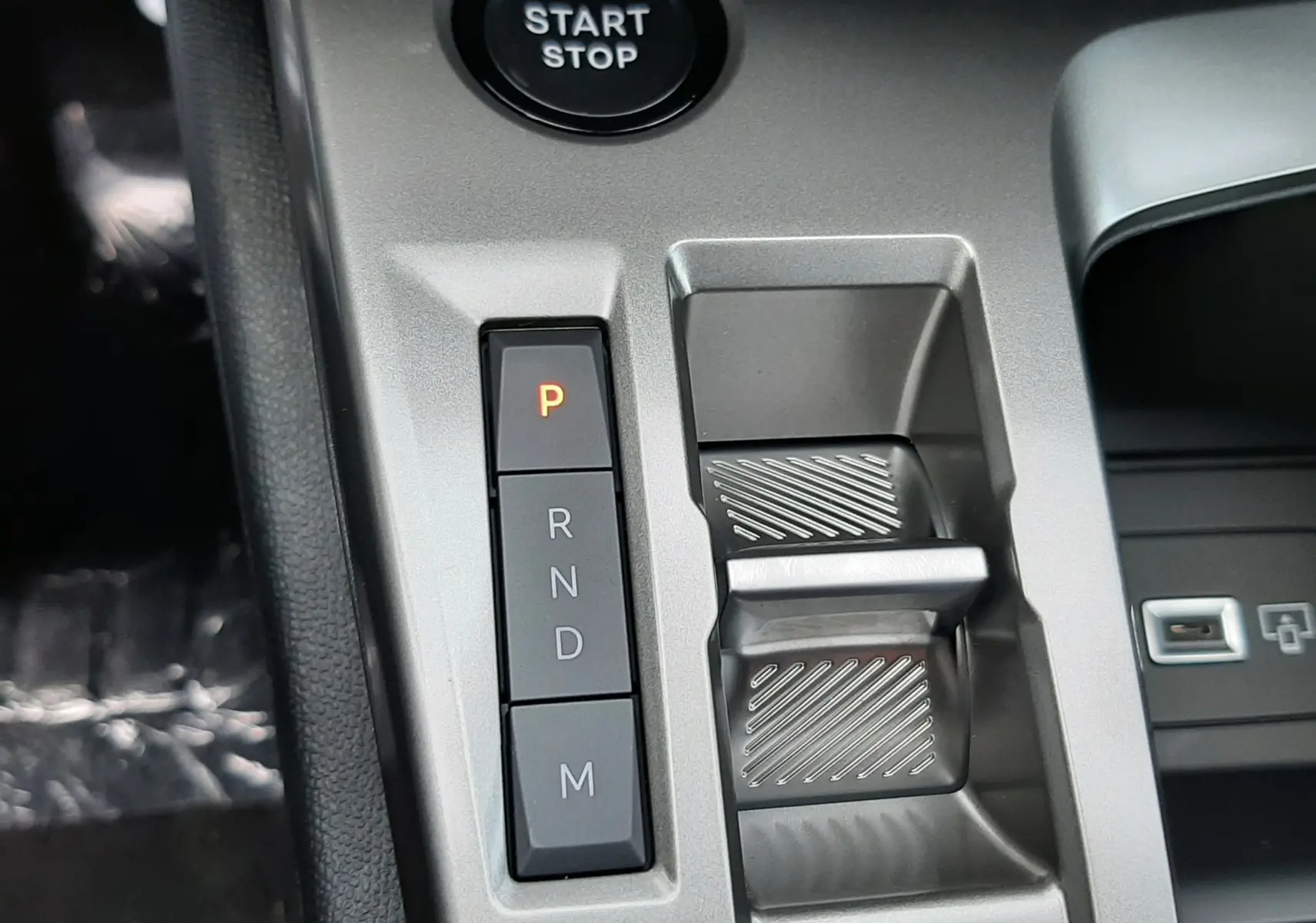 Gros plan sur la console centrale de la Peugeot 308 hybride 2025 avec boutons de boîte auto et bouton start/stop.