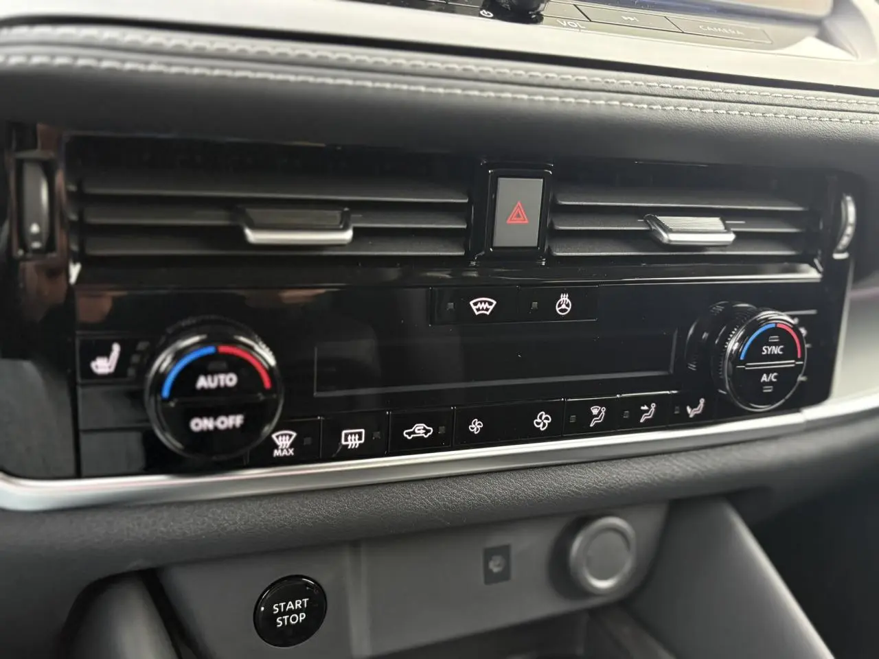 Vue rapprochée de la console centrale noire du Nissan Qashqai 2025, montrant les commandes de climatisation et le bouton Start/Stop.