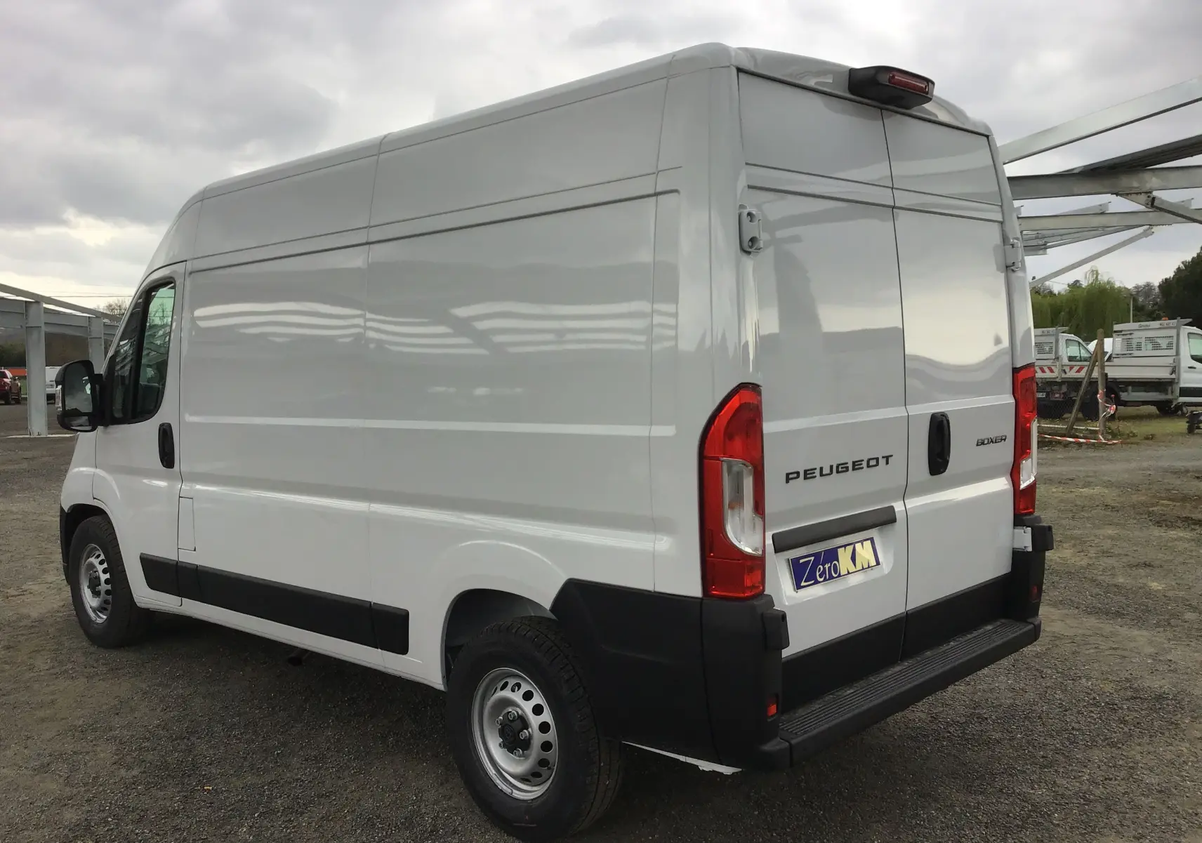 Vue 3/4 arrière droite d'un Peugeot Boxer Fourgon blanc 2025 avec hayon arrière et pare-chocs noir.