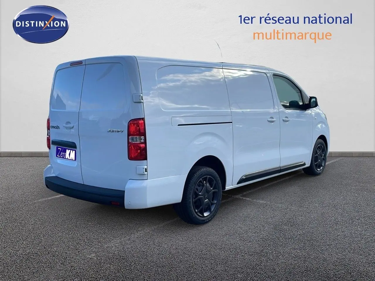 Vue 3/4 arrière droite d'un Citroën Jumpy Fourgon XL blanc Kaolin avec jantes noires et portes latérales fermées.