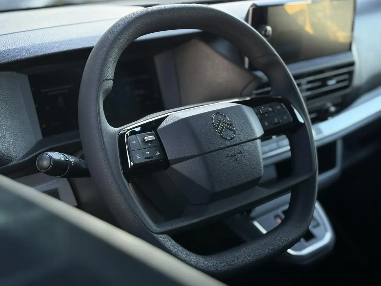 Volant noir avec commandes intégrées et logo Citroën, vue rapprochée de l'habitacle moderne du Jumpy XL gris Titane.