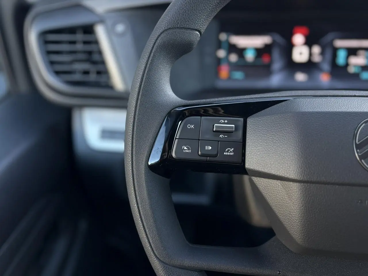 Gros plan sur les commandes au volant à gauche du Citroën Jumpy XL gris Titane, tableau de bord flou en arrière-plan.