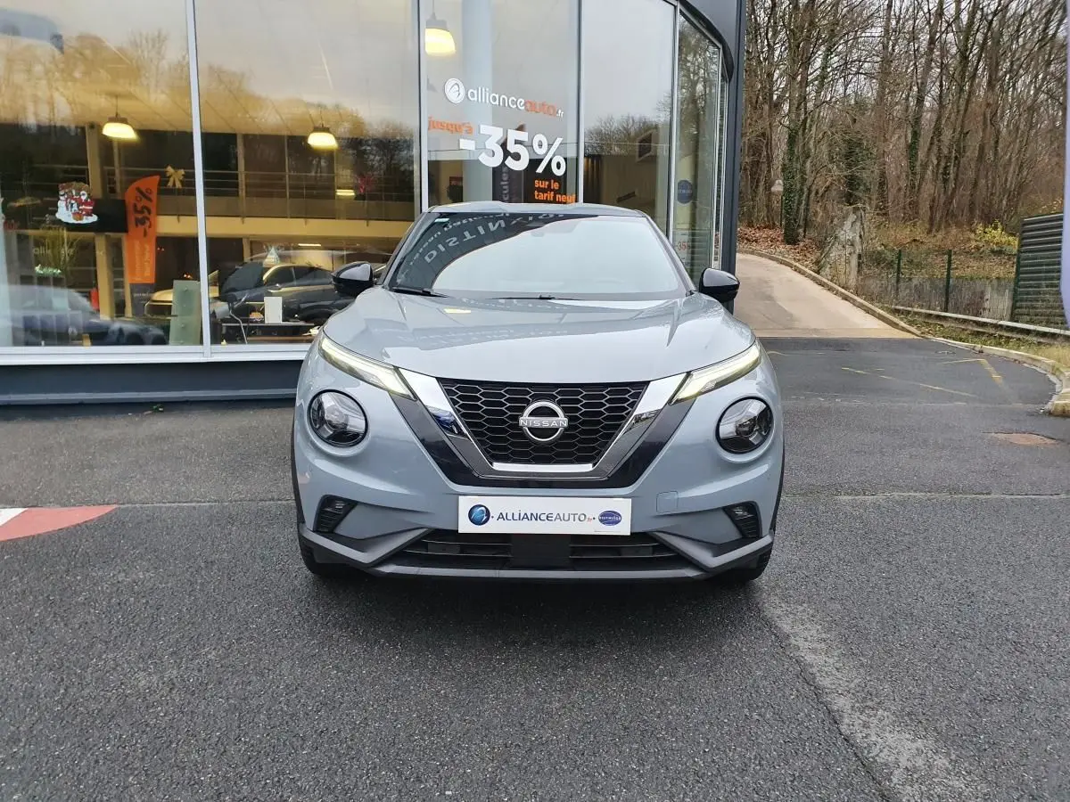 Nissan Juke gris céramique vue de face, mettant en valeur sa calandre en V et ses phares ronds distinctifs.