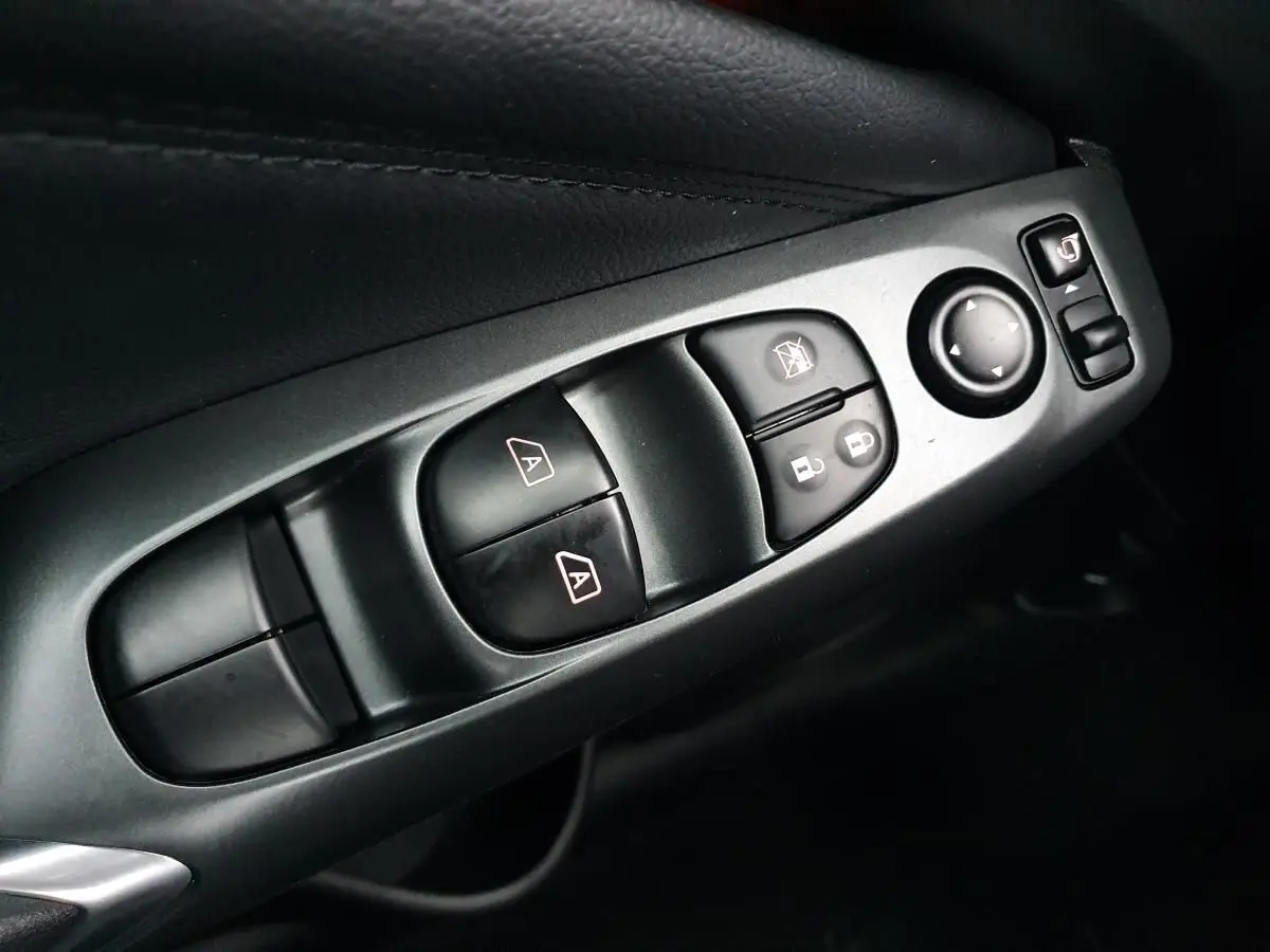 Gros plan sur les commandes de lève-vitres et rétroviseurs côté conducteur du Nissan Juke gris céramique 2025.