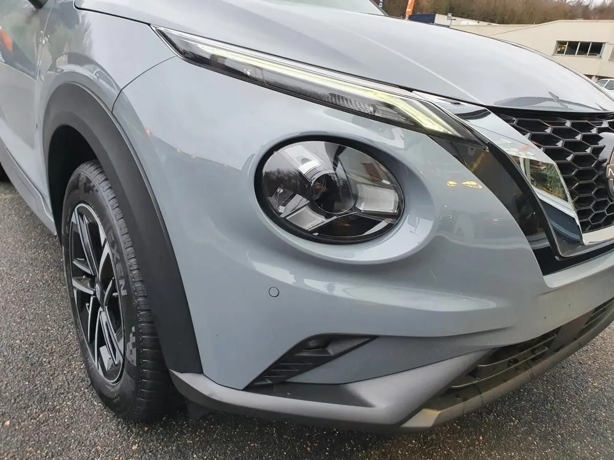 Gros plan sur l'avant droit gris céramique du Nissan Juke 2025 avec phares ronds et calandre en nid d'abeille.
