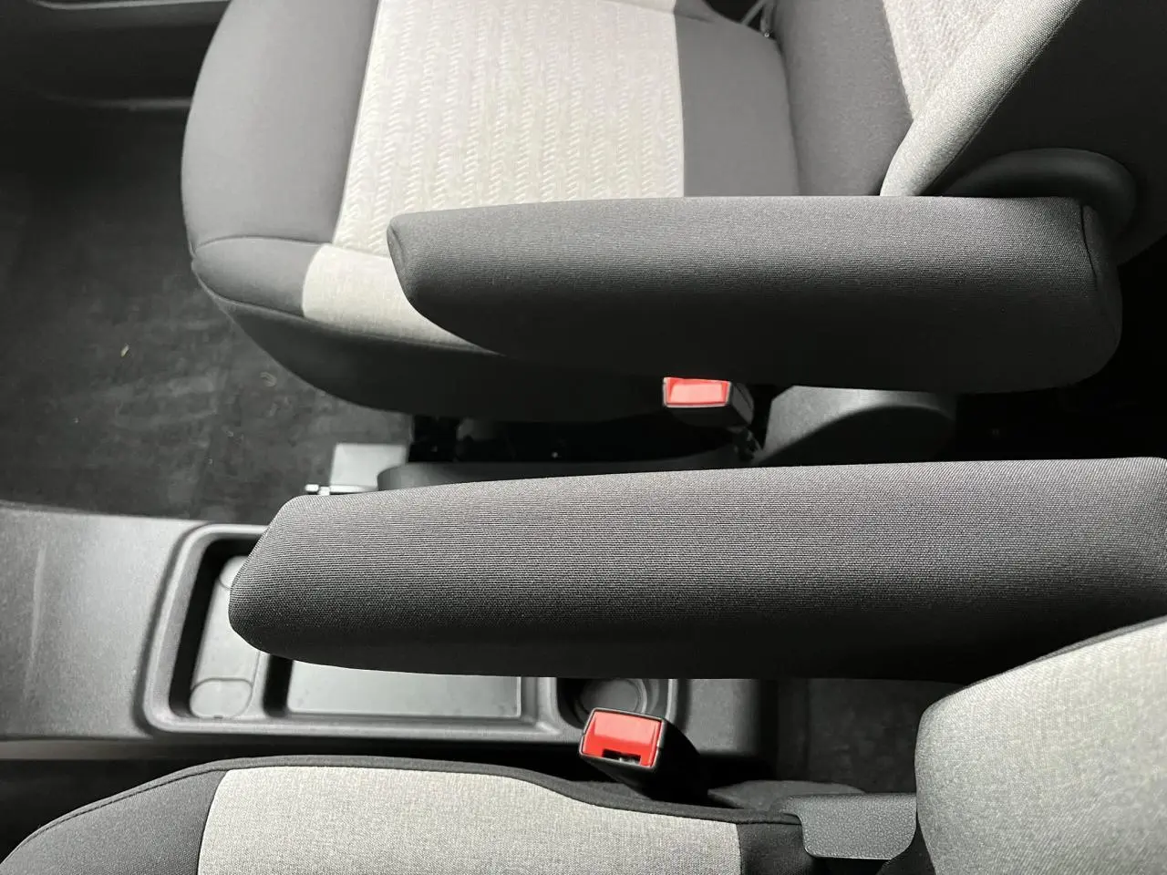 Vue rapprochée des accoudoirs noirs et sièges bicolores gris clair et foncé du Citroën Berlingo Multispace blanc Glacier.