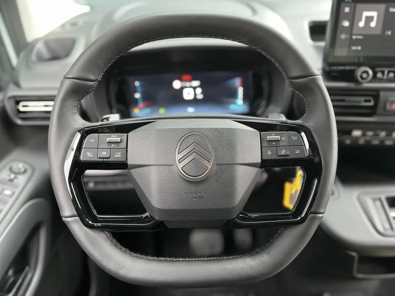 Vue rapprochée du volant cuir multifonctions du Citroën Berlingo Multispace 2025 avec tableau de bord numérique en arrière-plan.