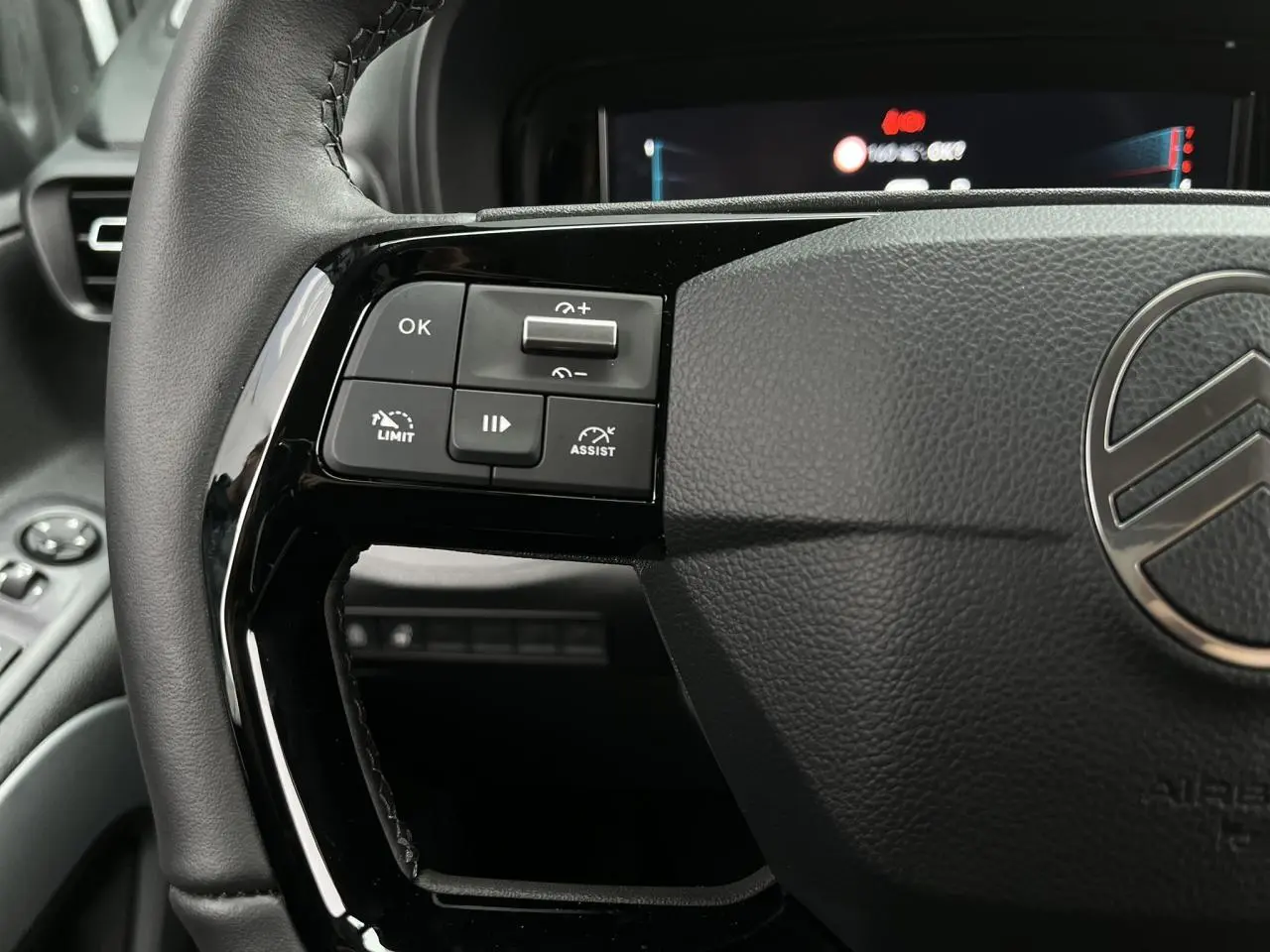 Gros plan sur le volant cuir du Citroën Berlingo Multispace blanc, avec commandes multifonctions visibles à gauche.