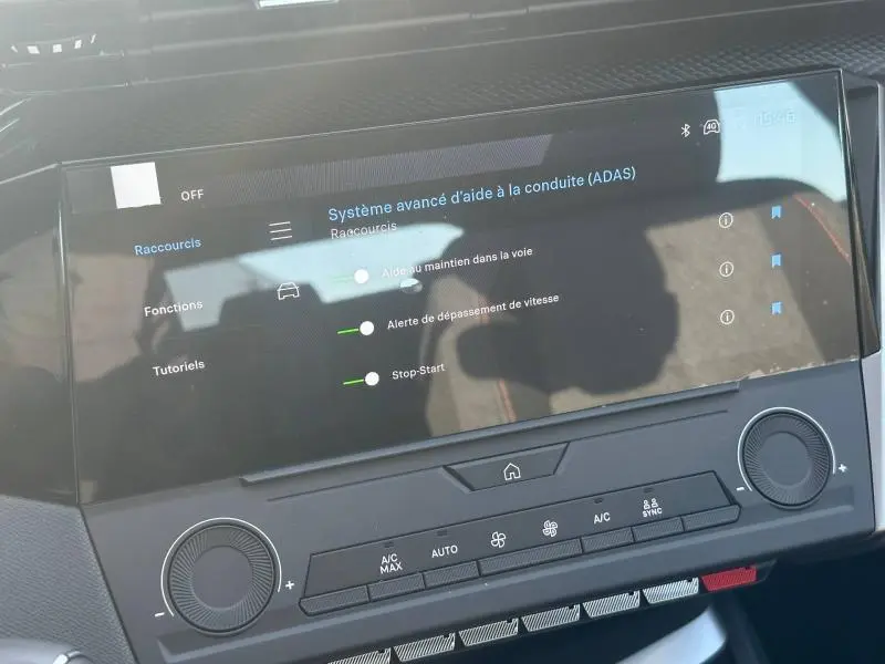 Vue rapprochée de l'écran tactile central affichant les réglages d'aide à la conduite dans l'habitacle d'une Peugeot 308 bleu.