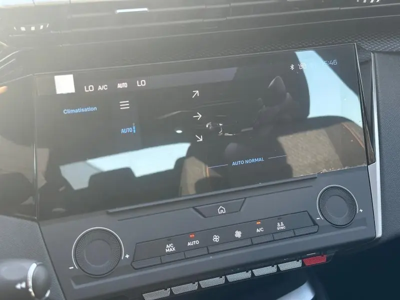 Écran tactile central de la Peugeot 308 bleu, vue rapprochée du tableau de bord avec commandes climatisation visibles.