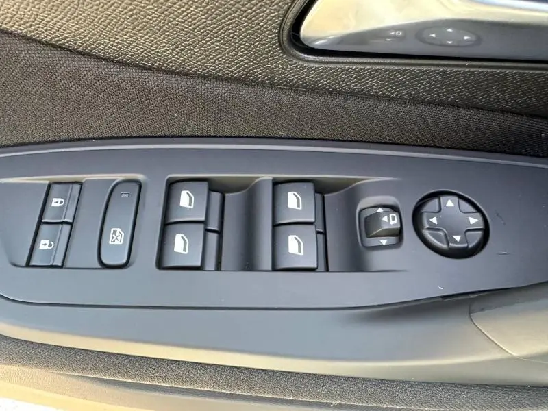 Panneau de commande des vitres et rétroviseurs côté gauche intérieur d'une Peugeot 308 bleu 2025.