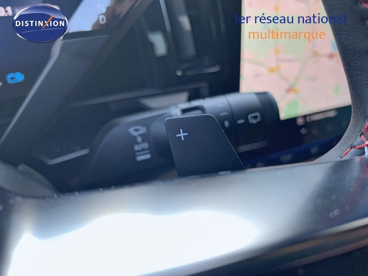 Gros plan sur la palette de changement de vitesses "+" du volant d'un Renault Austral blanc métal au toit noir, intérieur moderne.