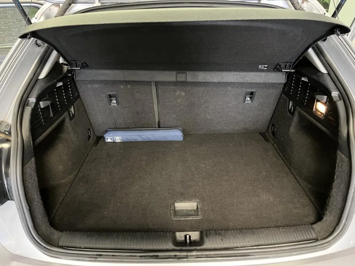 Coffre ouvert de l'Audi Q2 gris, vue arrière montrant un espace de chargement propre et éclairé à droite.