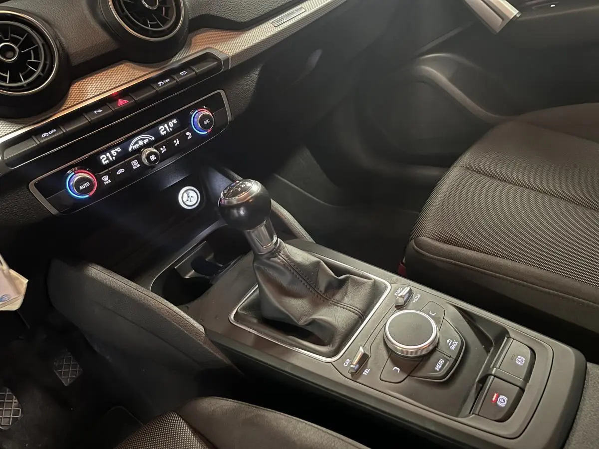 Intérieur de l'Audi Q2 2019 vu côté passager, avec levier de vitesse manuel et commandes de climatisation visibles.