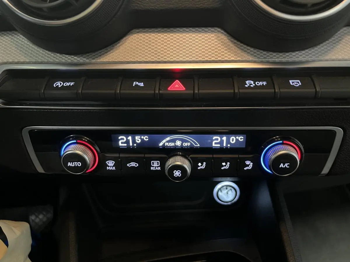 Détail de la console centrale de l'Audi Q2 gris, avec commandes de climatisation automatique et boutons fonctionnels.