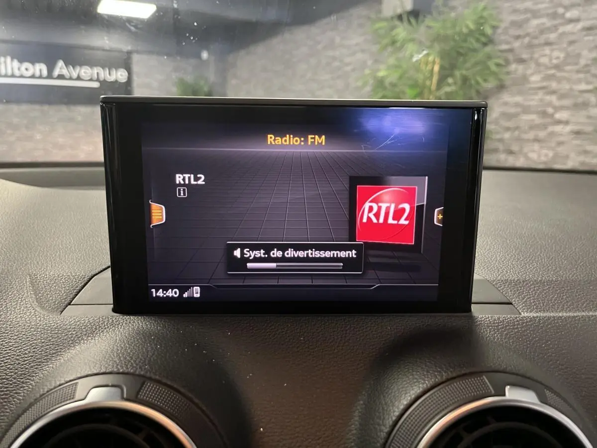 Écran central multimédia affichant la radio FM RTL2 sur le tableau de bord de l'Audi Q2 gris.