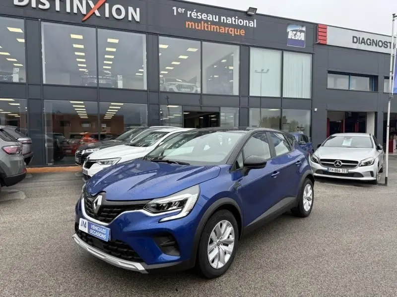 Renault Captur E-Tech 145 Zen bleu métal en 3/4 avant droit, garé devant un concessionnaire multimarque.