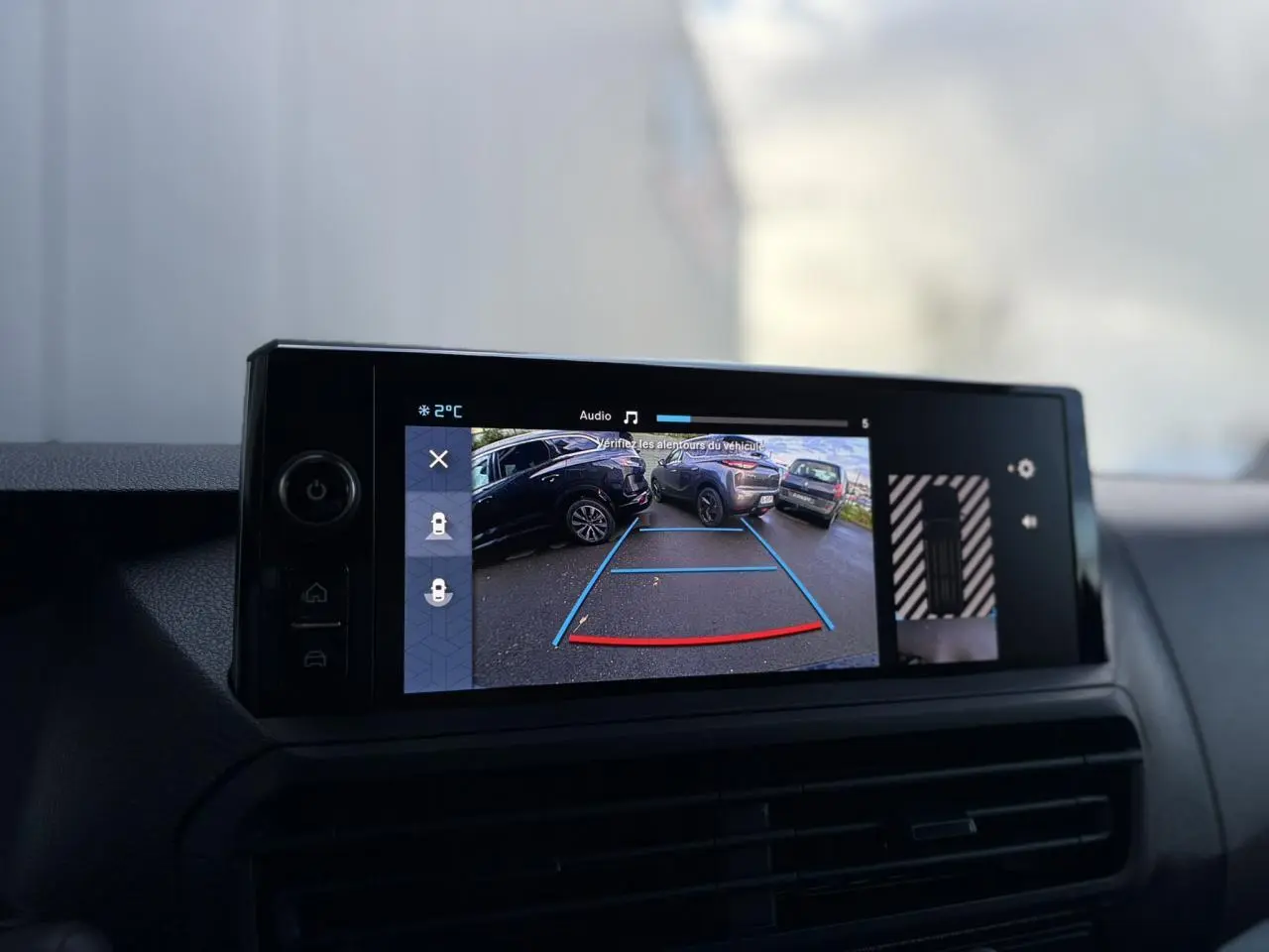 Écran tactile intérieur montrant la caméra de recul du Citroën Jumpy gris Artense avec repères de stationnement colorés.