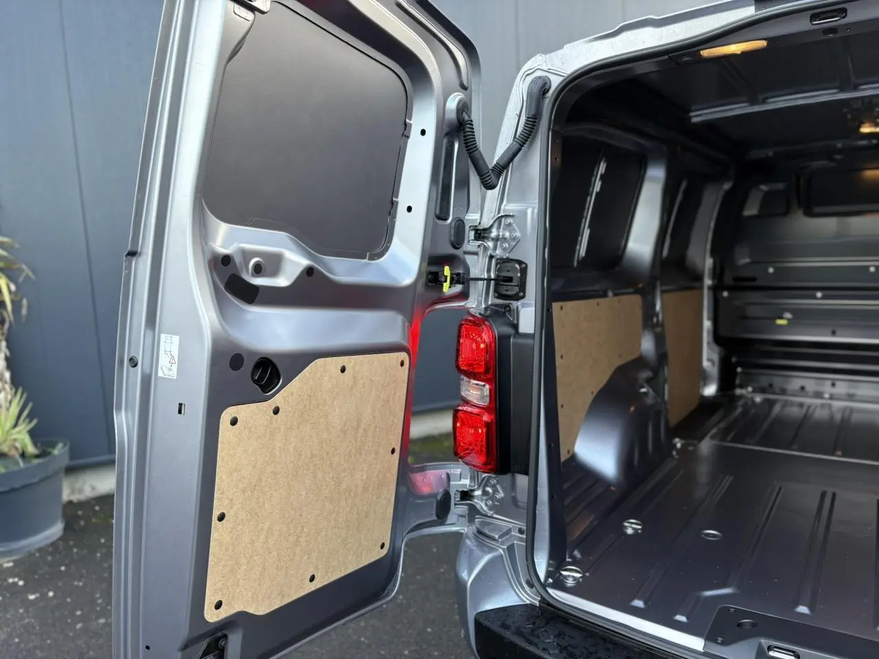 Vue arrière ouverte côté droit du Citroën Jumpy XL gris Artense, montrant l'espace de chargement vide et les panneaux intérieurs en bois.