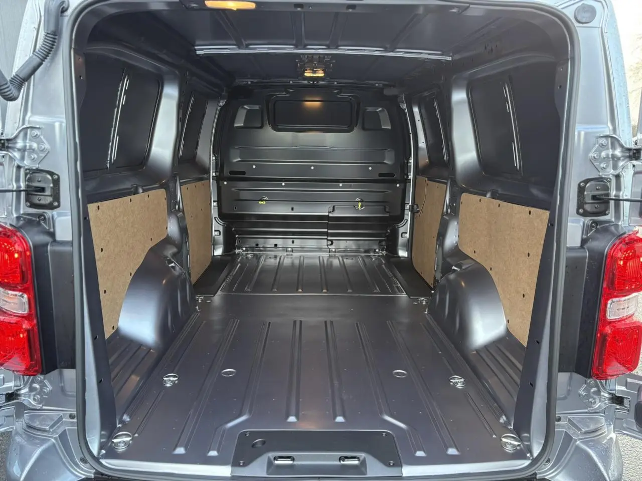 Vue arrière ouverte du Citroën Jumpy XL gris Artense montrant l'espace de chargement tôlé et les panneaux latéraux en bois.