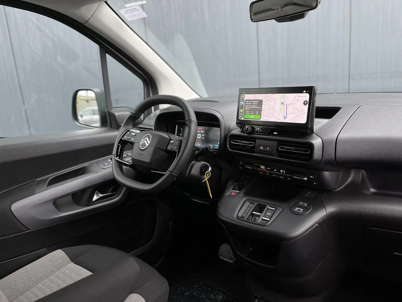 Vue intérieure côté conducteur du Citroën Berlingo Multispace 2025, tableau de bord noir avec écran tactile et volant multifonctions.
