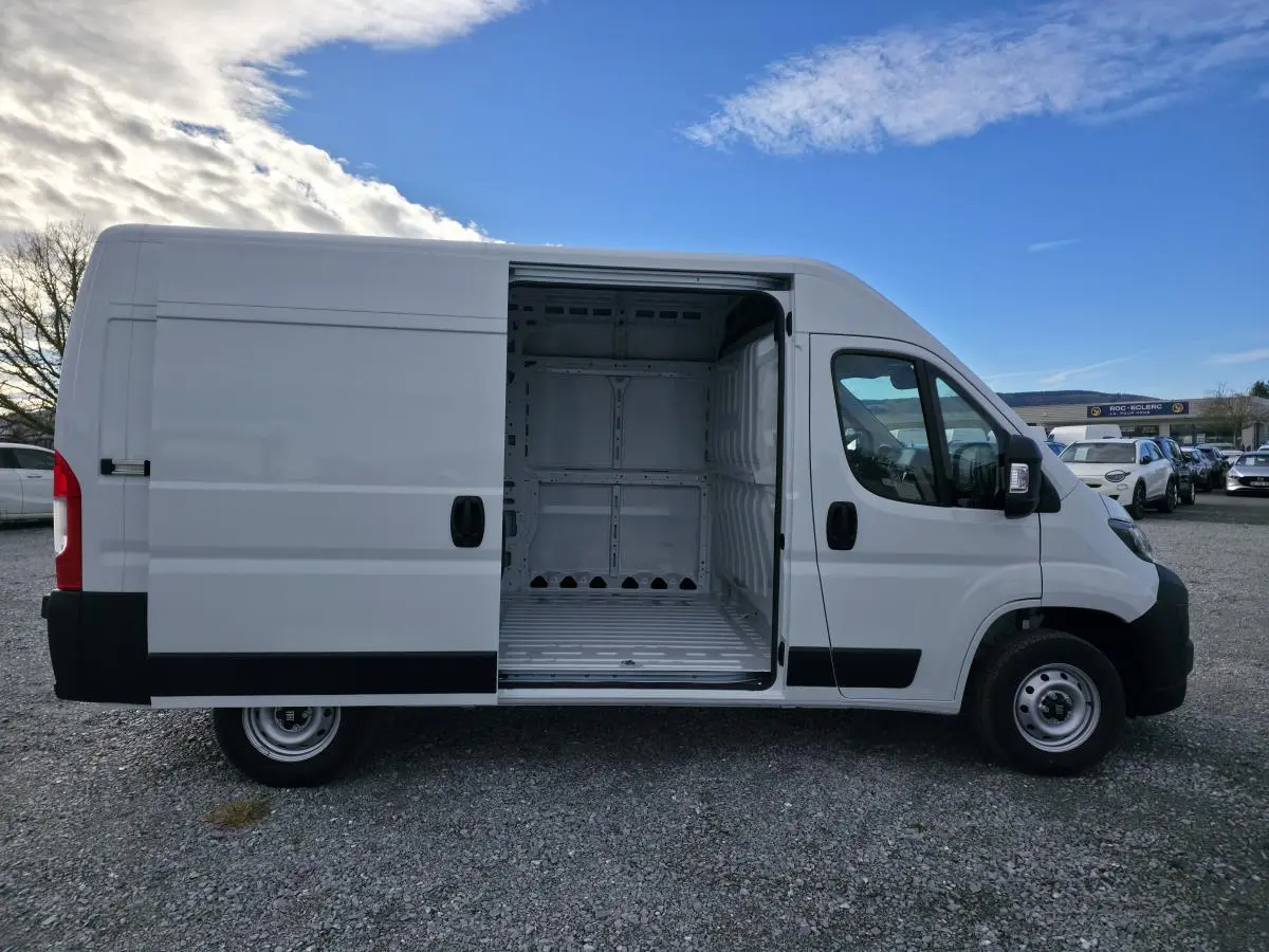 Vue latérale droite d'un FIAT Ducato Fourgon blanc 2025 avec porte coulissante ouverte montrant l'intérieur tôlé vide.