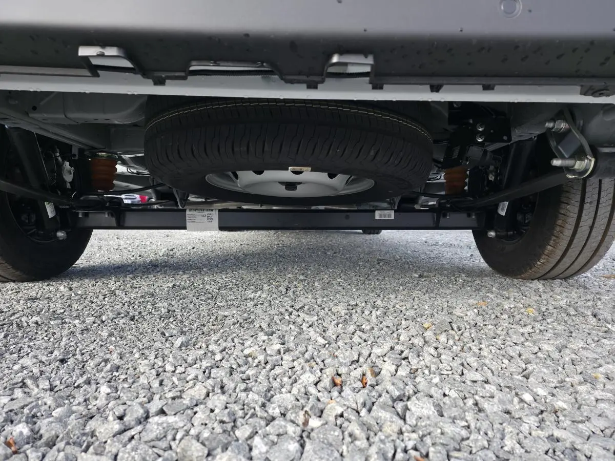 Vue en contre-plongée sous le Fiat Ducato Fourgon blanc, mettant en valeur la roue de secours et le châssis arrière.